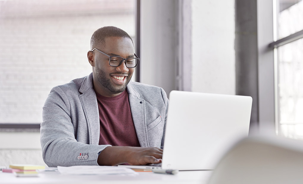 Businessperson smiling while typing on computer at desk