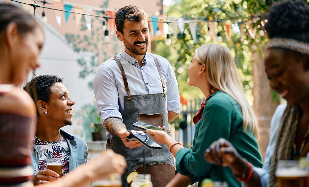 Group of people at a restaurant table with one person paying server
