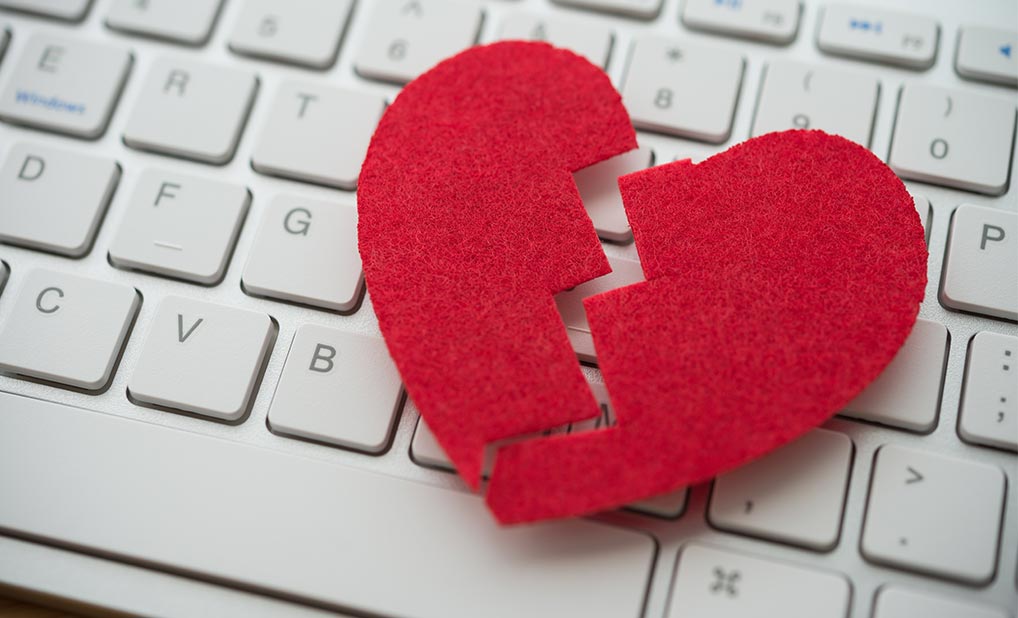 Close-up of a broken felt heart placed on a laptop keyboard