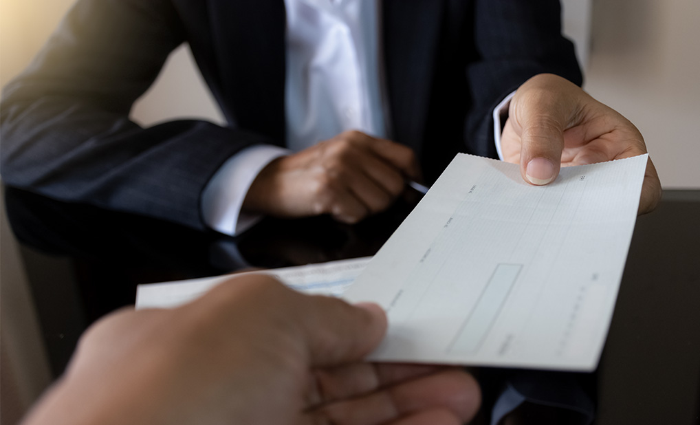 Close up of person handing a check to another person