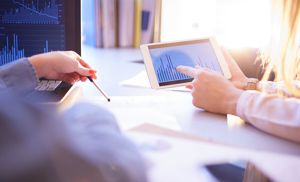 Close up of people reviewing data on tablet