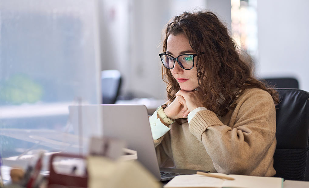 Person looking intently at laptop on desk in office