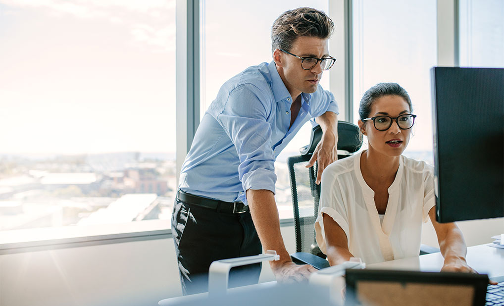 Two businesspeople looking at computer screen together