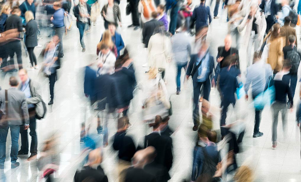 Crowd of people in large hall, blurred to show movement