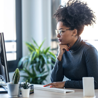 a girl sitting at a desk examining a computer screen