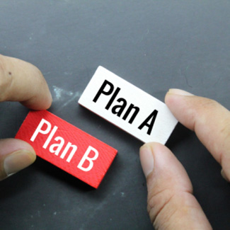 Hands holding tiles that say 'Plan A' and 'Plan B'