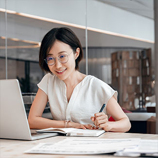 A woman is taking notes in front of a computer