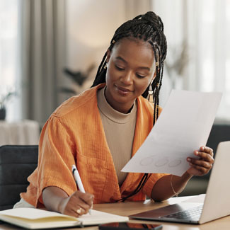 woman holding a sheet of paper and writing in a notebook